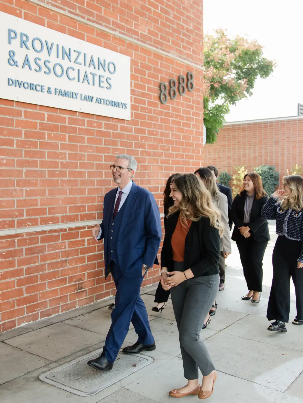 Provinziano & Associates - a group of people walking in front of a brick building