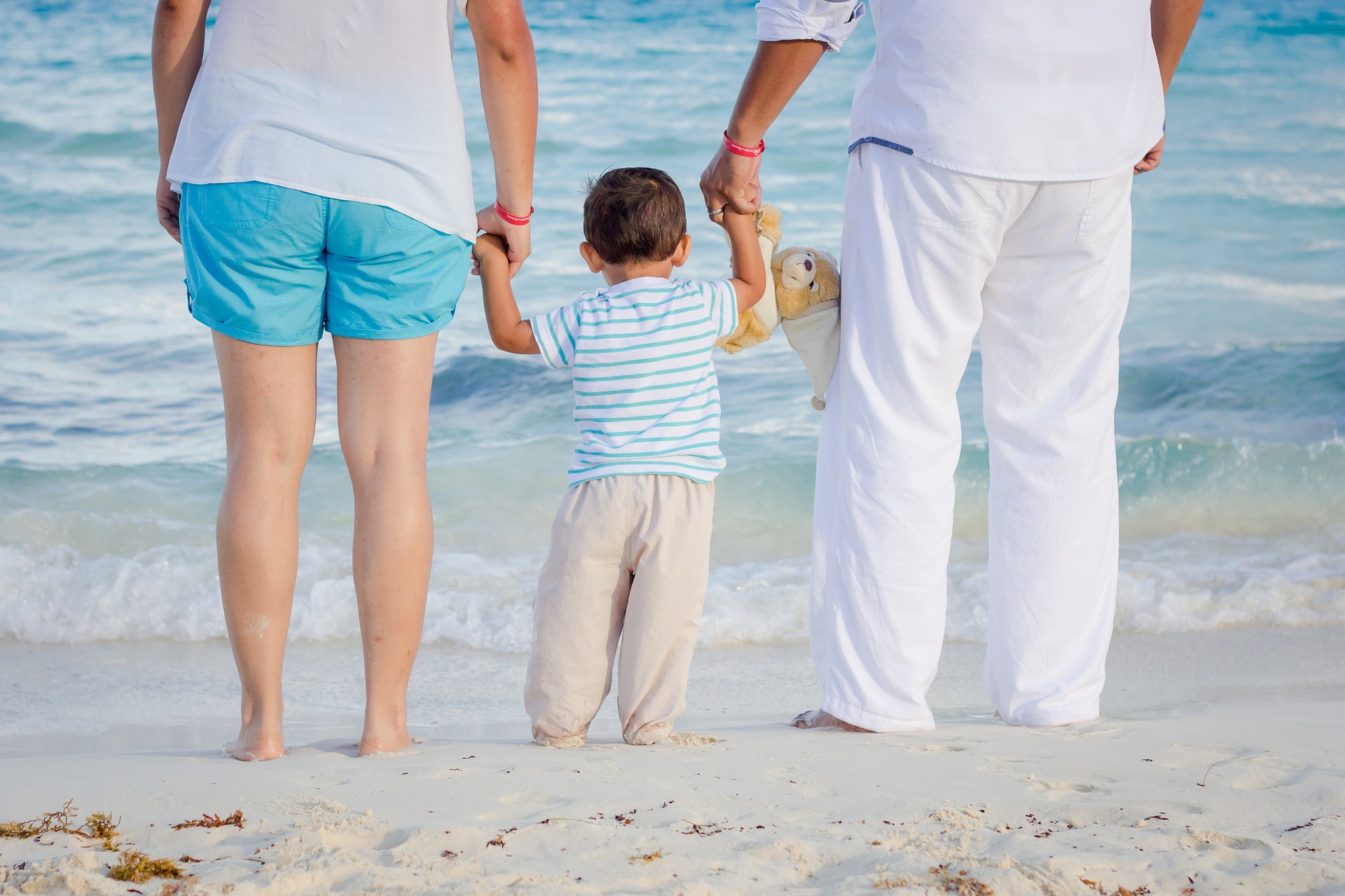 A child holding hands with two adults, symbolizing the care, support, and legal responsibilities involved in guardianship and custody arrangements