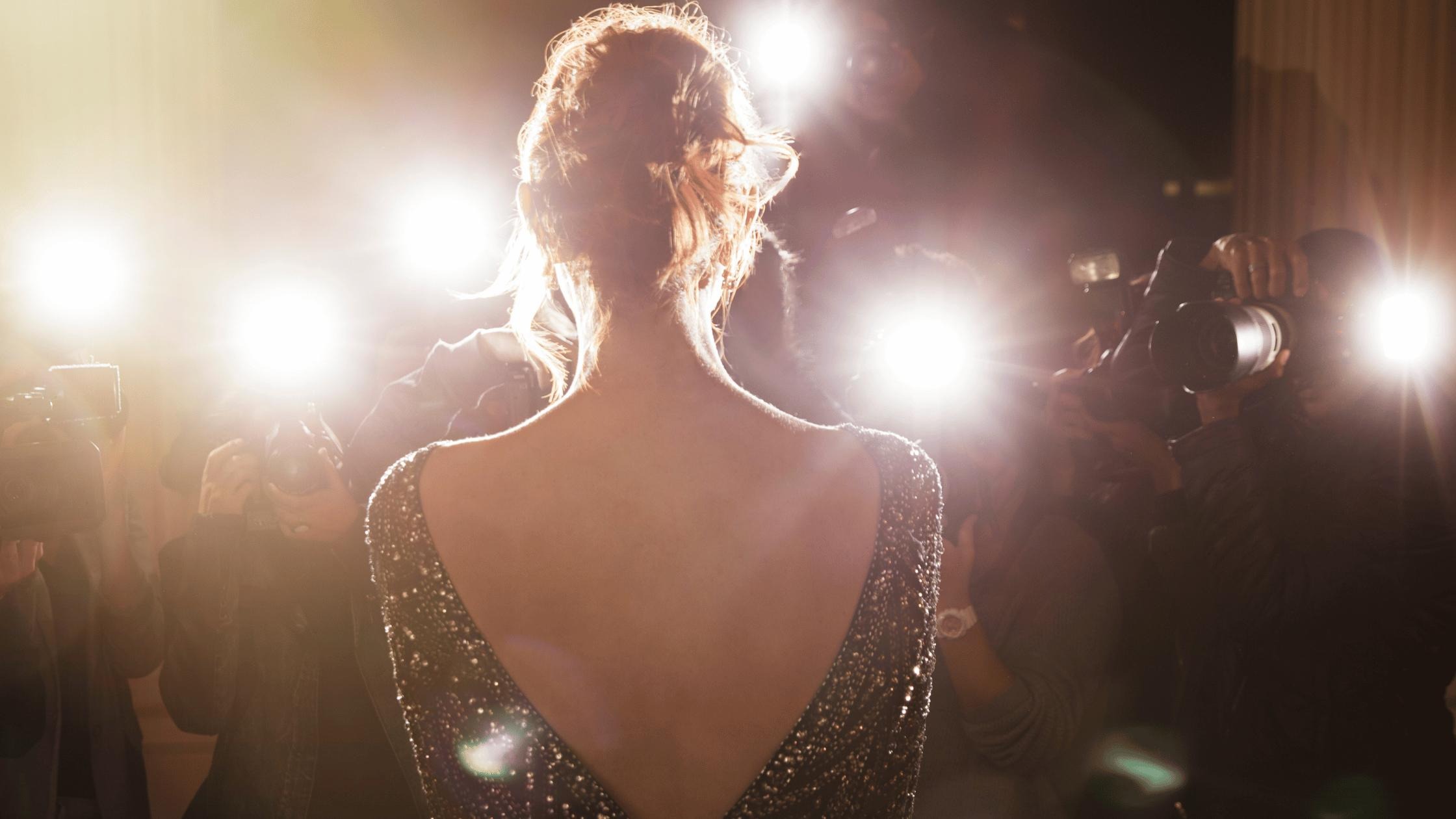 Back view of a famous person facing bright paparazzi lights, symbolizing public scrutiny and privacy concerns during celebrity divorces.