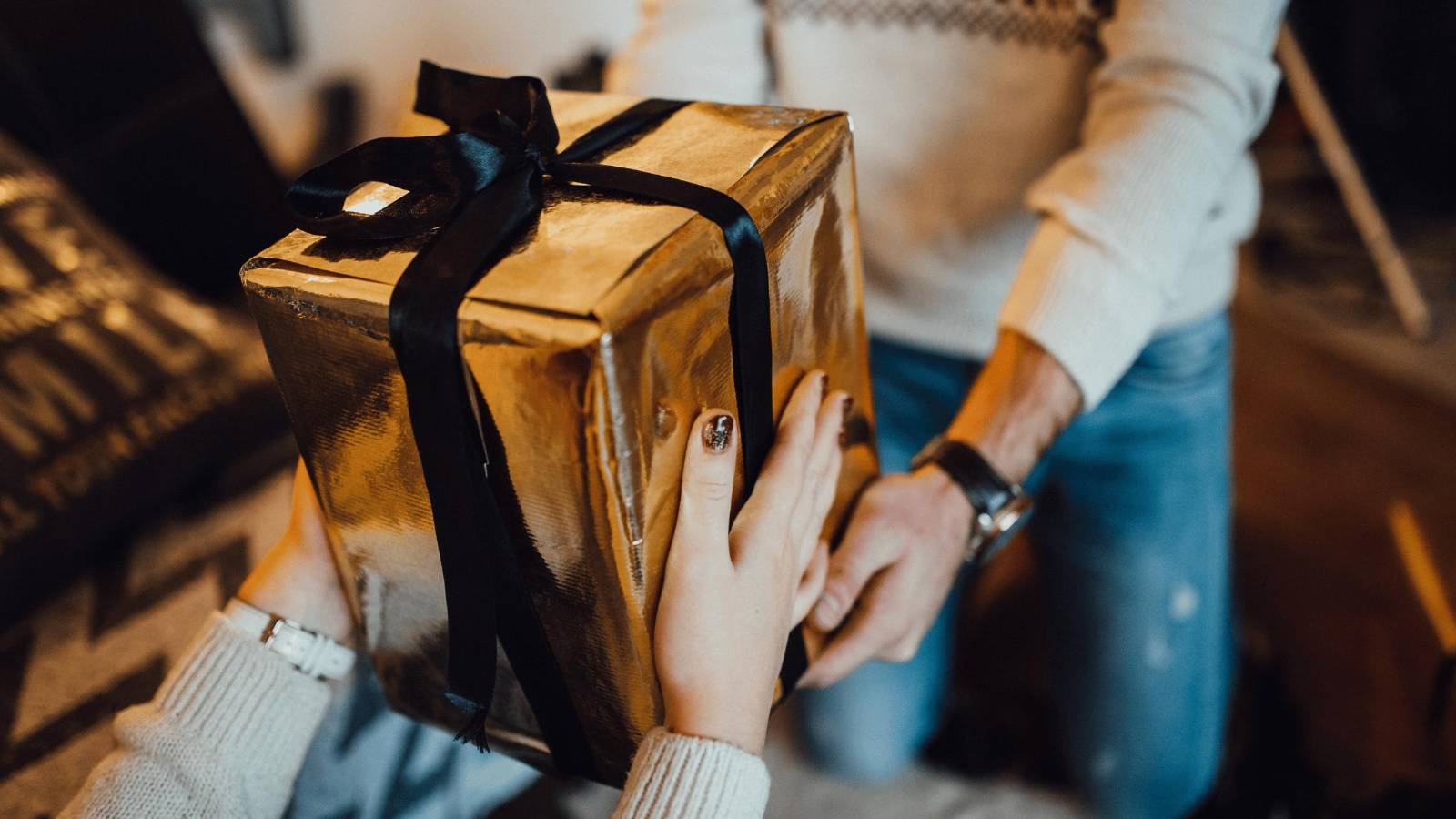 A gold-wrapped gift being exchanged between two people