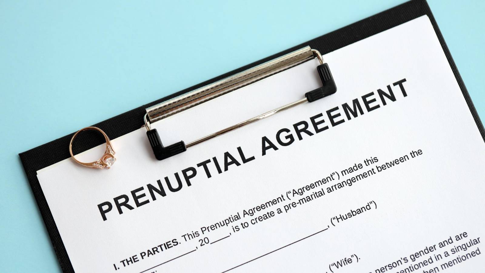 Prenuptial agreement document on a clipboard with a ring