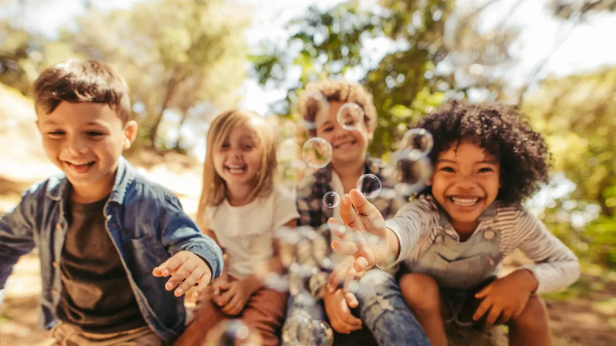 Four smiling children playing with bubbles outdoors