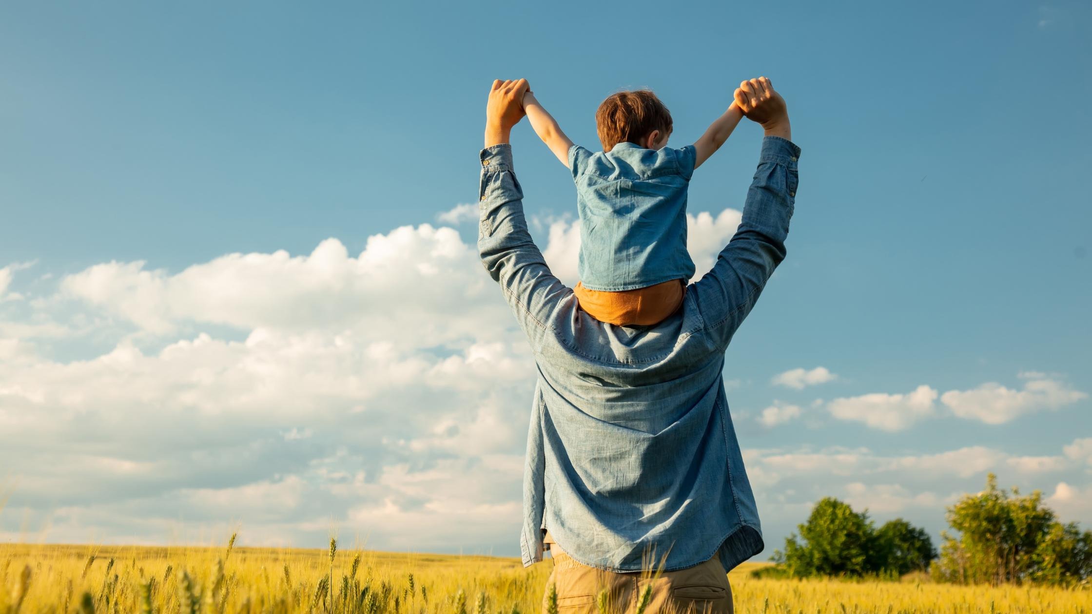 Man holding a child on his shoulders in a field, symbolizing the emotional connection that may impact legal parenthood in sperm donor cases.
